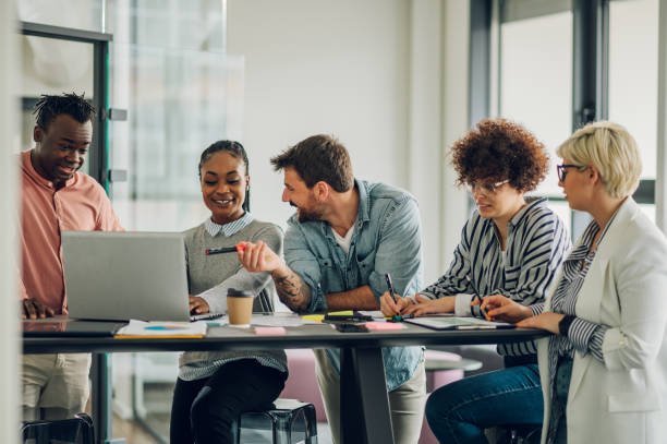Multiracial young creative people in a modern office while using a laptop. Group of diverse business people working together in the creative co-working space.
